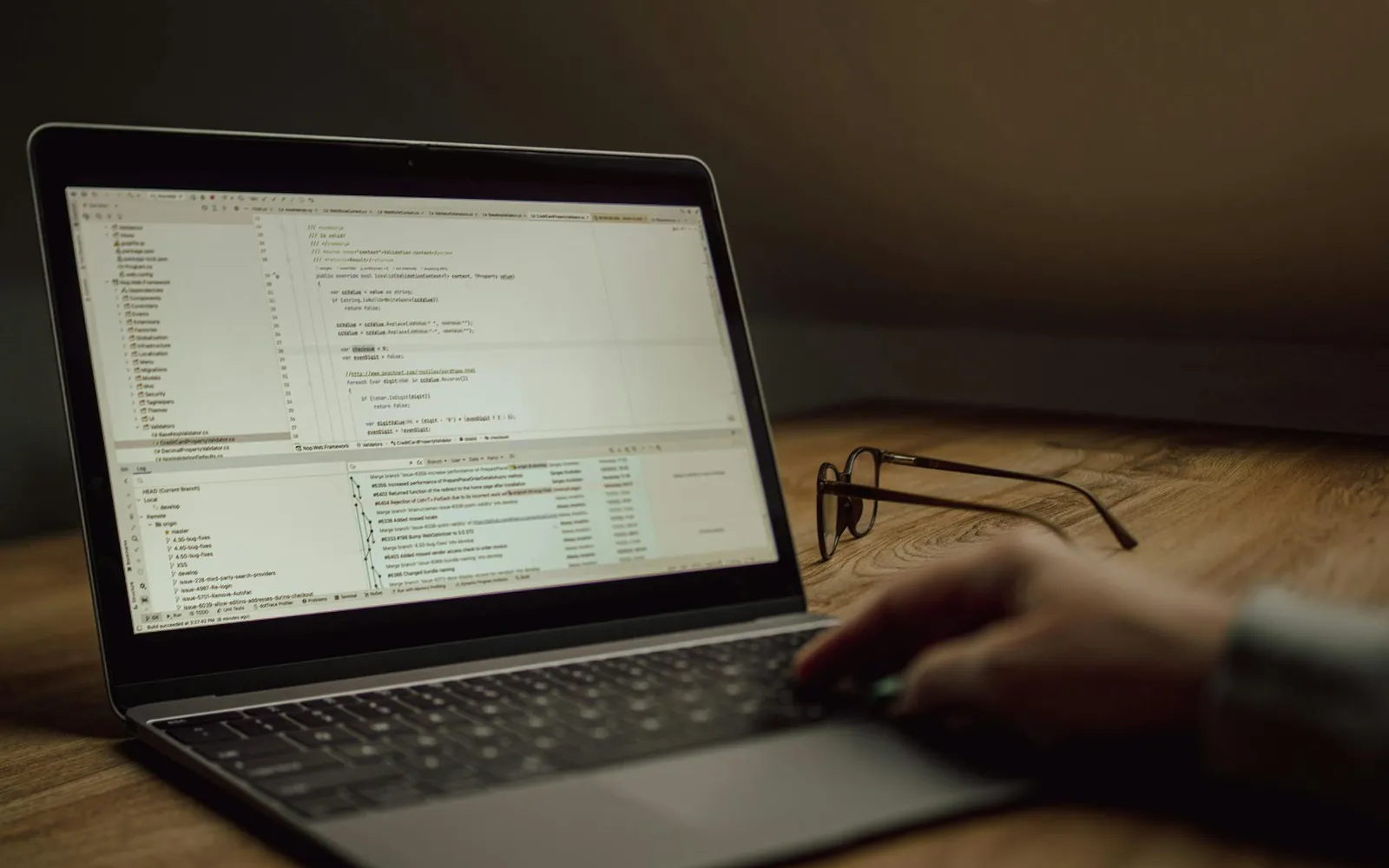 Notebook sobre uma mesa de madeira exibindo código em um editor, com óculos ao lado