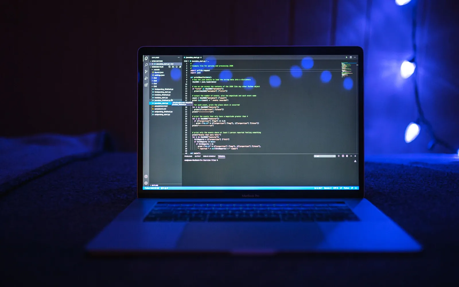 Um laptop sobre uma mesa mostrando linhas de código, iluminado em azul