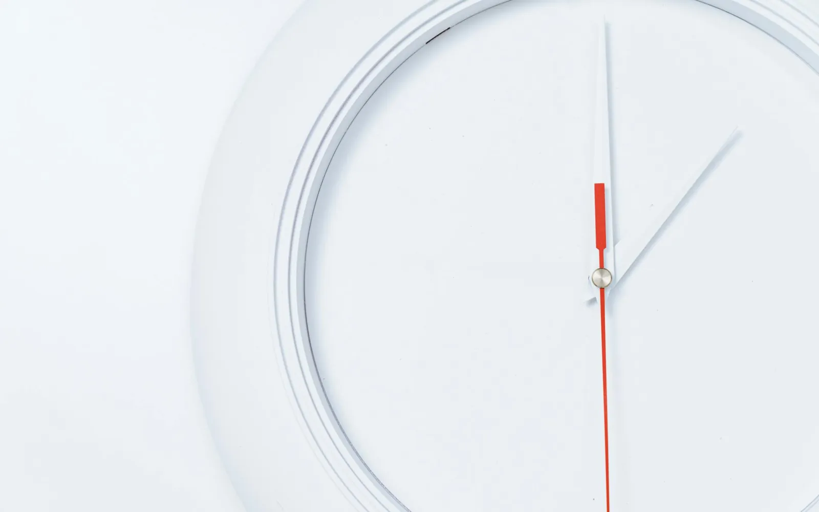 Close de um relógio de parede branco e minimalista com o ponteiro dos segundos vermelho